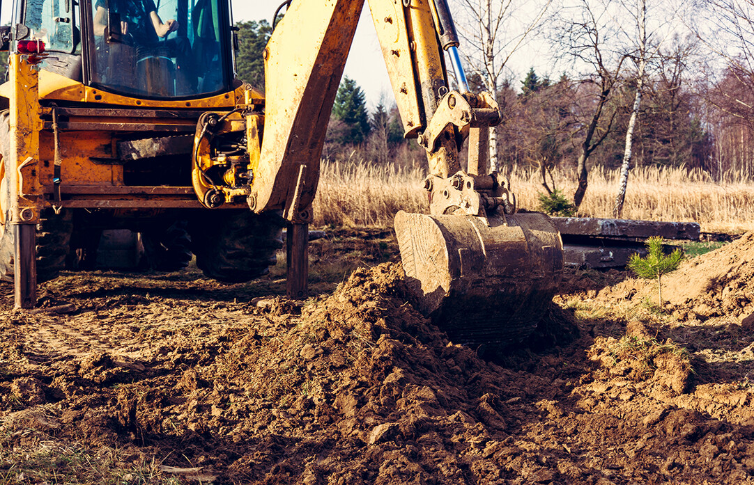 Ein Bagger hebt Erde auf einer Baustelle aus, um Platz für Bodenuntersuchungen zu schaffen.